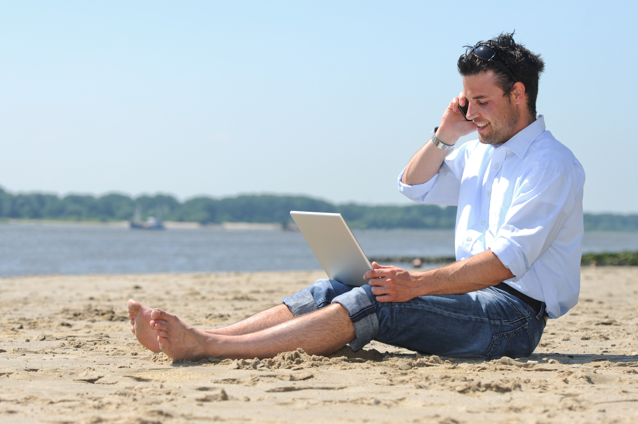 Am Strand mit Laptop und Smartphone und damit Urlaub und Arbeit verbinden. Arbeitgeber fürchten oft noch den Kontrollverlust und stehen Workation skeptisch gegenüber. Dabei bietet es Chancen für beide Seiten. 